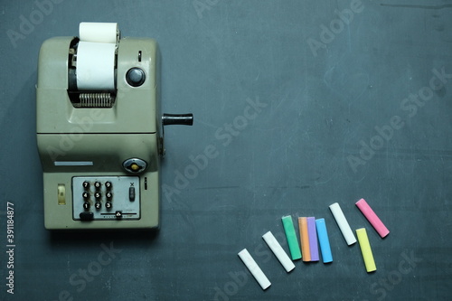 Vecchia calcolatrice su sfondo lavagna con gessettie spazio per scrivere testo photo
