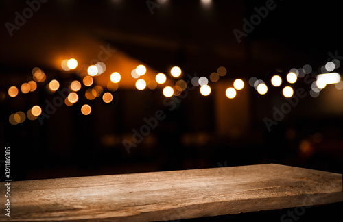 empty wooden table on blurred light gold bokeh of cafe restaurant on dark background, place for your products on the table