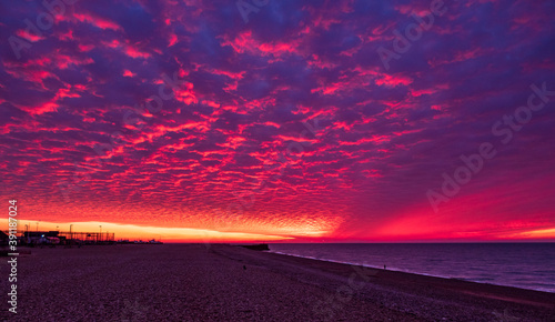 Dramatic November red dawn and mackerel clouds sky over Hastings beach front in east Sussex south east England