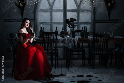 Bloodthirsty female vampire in red dress. Medieval interior
