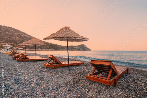 Foto Sunbeds and sun umbrellas await vacationers on the shingle beach at Ovabuku beach on the Datca Peninsula in Turkey