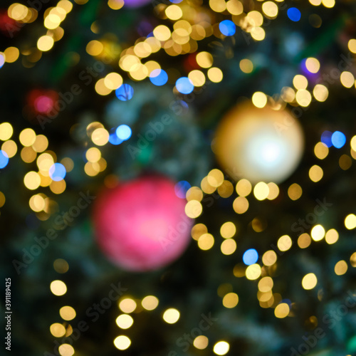 Background of blurred christmas tree in the light of garlands  balls and decorations for the new year
