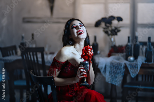 Fotografía Bloodthirsty female vampire in red dress. Medieval interior