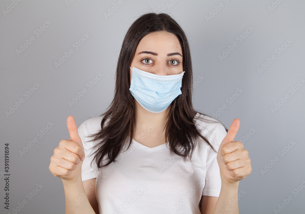Portrait of young woman wearing medical mask at gray background. Coronavirus concept. Portrait of young woman wearing medical mask at gray background. Coronavirus concept.