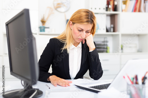 Obraz na plátne Focused young woman working with laptop and documents in modern office