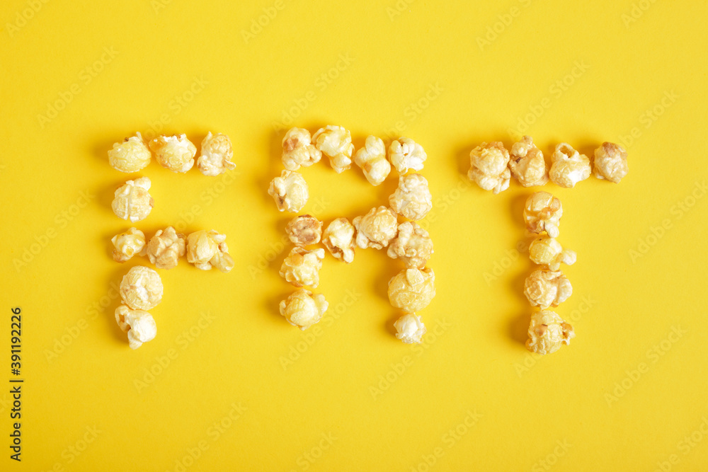 inscription fat made of popcorn on a yellow background top view inscription fat made of popcorn on a yellow background top view