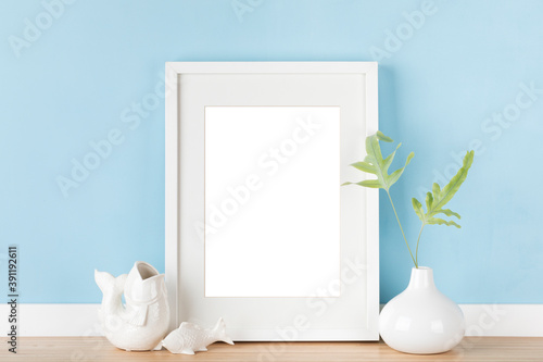 Elegant vertical white picture frame with matte poster artwork mockup template for online shop, japanese style decoration in front of pastel blue wall. Blank image area isolated with clipping path.