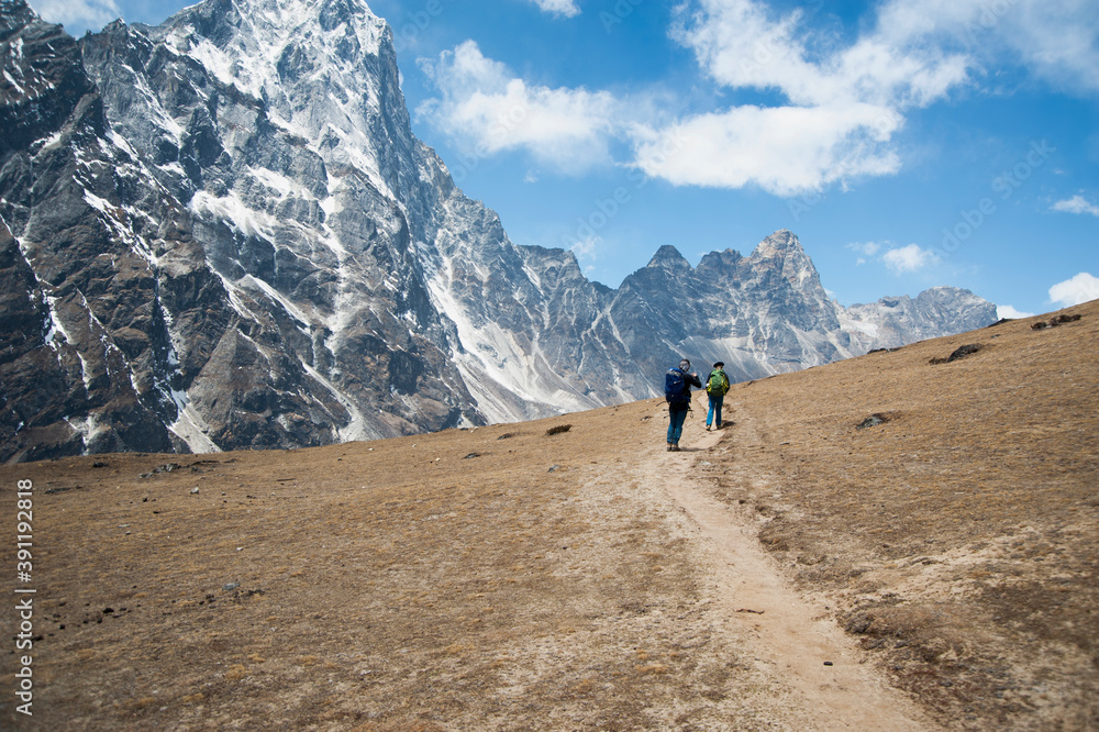 Two climbers on a path facing the steep mountains. Two climbers on a path facing the steep mountains.