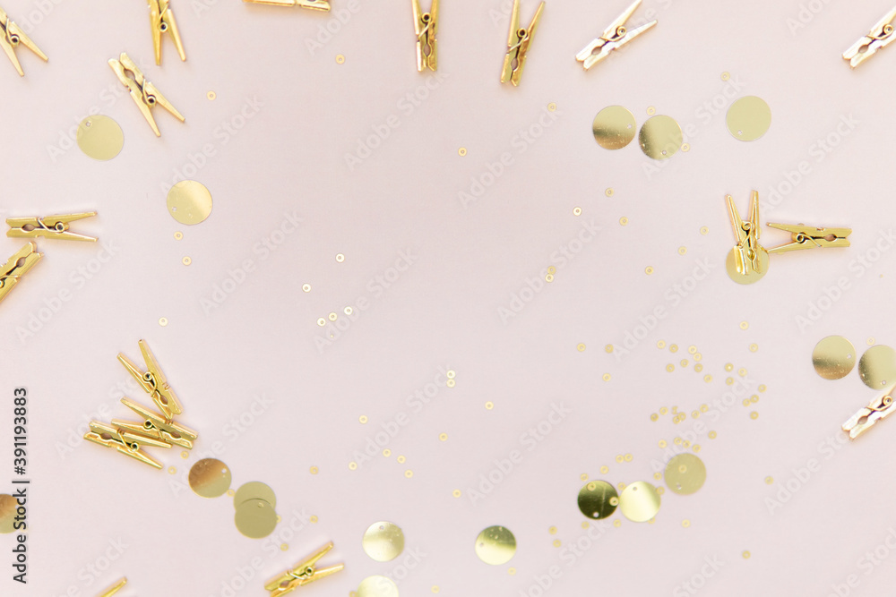 Fototapeta premium shiny gold clothespins and sequins on a pink background with a place to write. background for the holiday