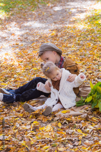 The elder brother and little sister are walking and laughing in the autumn park. Family and Children. Autumn mood 