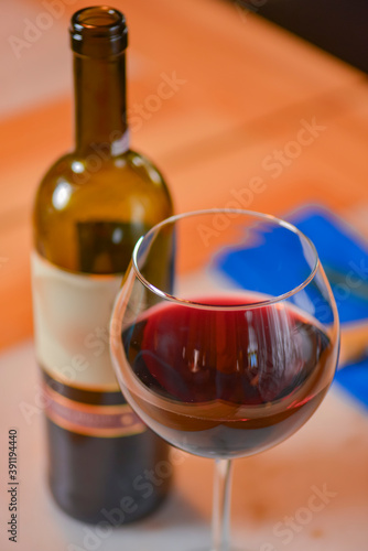 Wine glass and bottle of red wine on a wooden table over blurred background. Restaurant service, eating out concept.