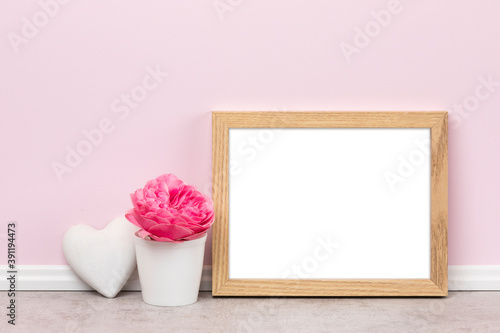 Background template, horizontal wooden picture frame heart-shaped ornament and rose blossom in front of pink wall. Blank image area isolated with clipping path.