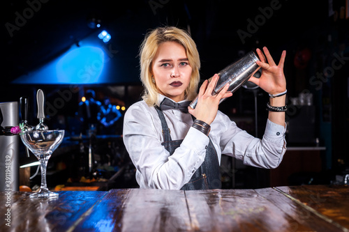 Pretty woman barman decorates colorful concoction while standing near the bar counter in bar photo