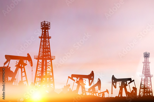Darck silhoutte of oil rig and pumps during sunset.