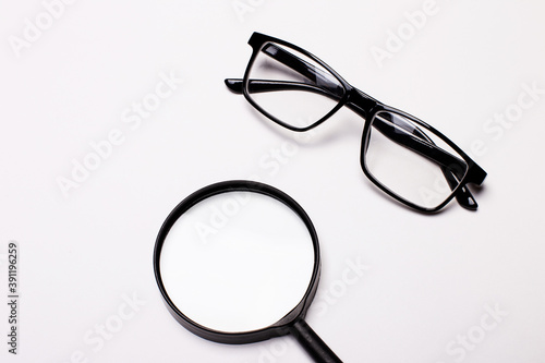 On the table are black-framed glasses and a magnifying glass. Business concept