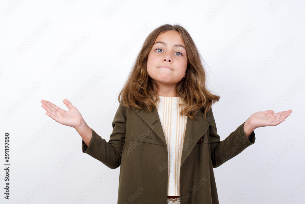 Maybe yes or no. Doubtful Beautiful little girl standing against white background, shrugs shoulders in bewilderment, tries to make decision puzzled what he wants. Hesitation and uncertainty. Maybe yes or no. Doubtful Beautiful little girl standing against white background, shrugs shoulders in bewilderment, tries to make decision puzzled what he wants. Hesitation and uncertainty.