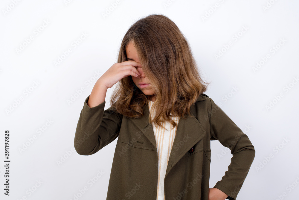 Very upset, charming, nice Beautiful little girl standing against white background, touching nose between closed eyes, wants to cry, having stressful relationship or having troubles with work Very upset, charming, nice Beautiful little girl standing against white background, touching nose between closed eyes, wants to cry, having stressful relationship or having troubles with work