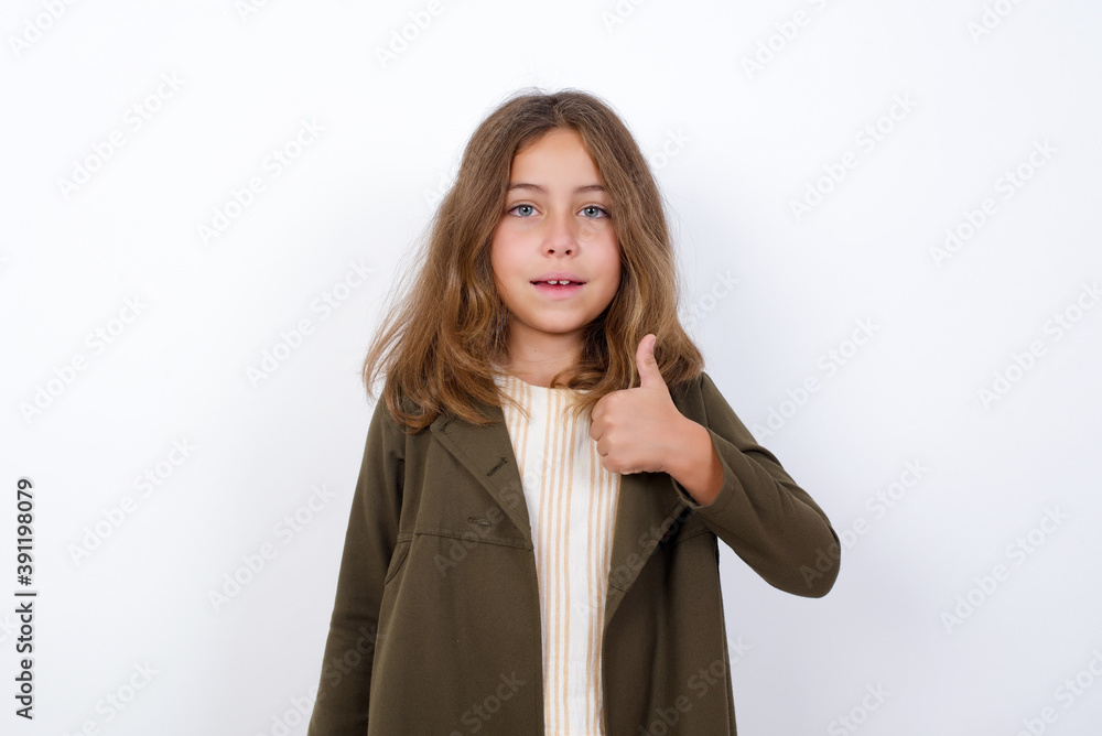 Beautiful little girl standing against white background, giving thumb up gesture, good Job! Positive human emotion facial expression body language. Beautiful little girl standing against white background, giving thumb up gesture, good Job! Positive human emotion facial expression body language.