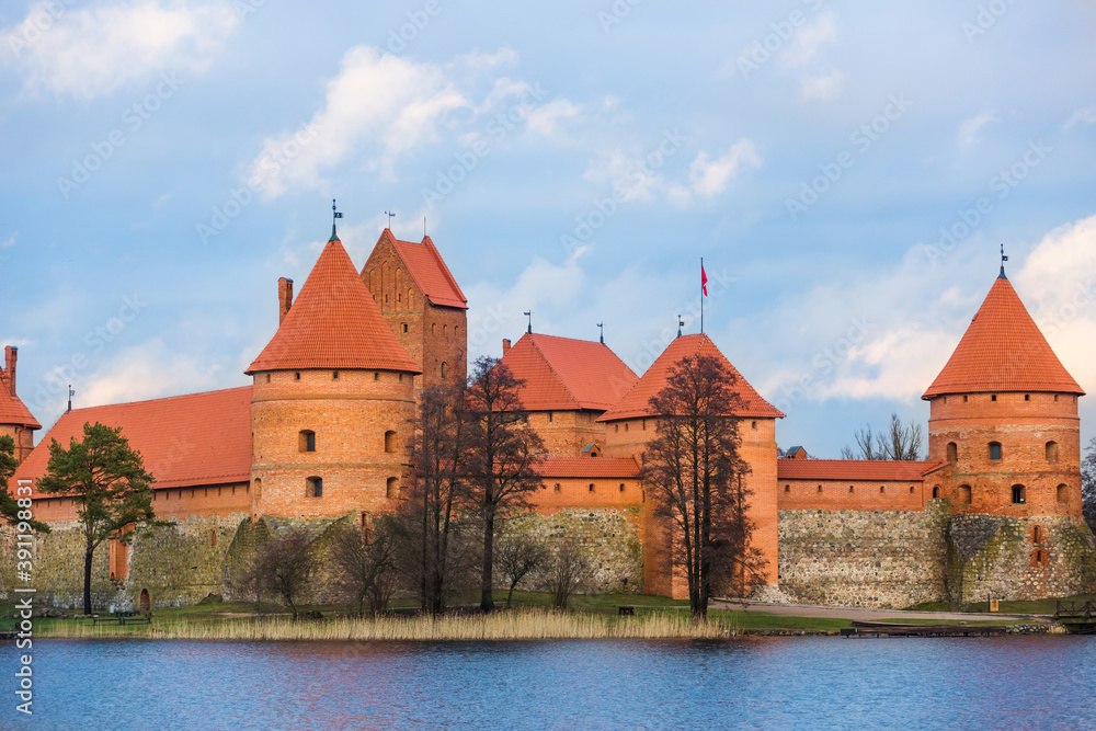 Trakai Island Castle in Lithuania. Brick fortress close up. Red turrets and walls. Panoramic view of the Lake Galve, blue sky and red brick towers. European castle, landmark of the Baltic region
