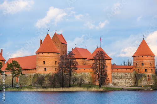 Trakai Island Castle in Lithuania. Brick fortress close up. Red turrets and walls. Panoramic view of the Lake Galve, blue sky and red brick towers. European castle, landmark of the Baltic region