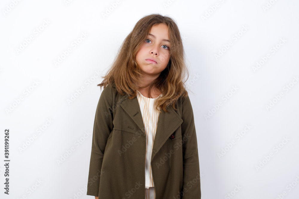 Gloomy, bored Beautiful little girl standing against white background, frowns face looking up, being upset with so much talking hands down, feels tired and wants to leave. Gloomy, bored Beautiful little girl standing against white background, frowns face looking up, being upset with so much talking hands down, feels tired and wants to leave.