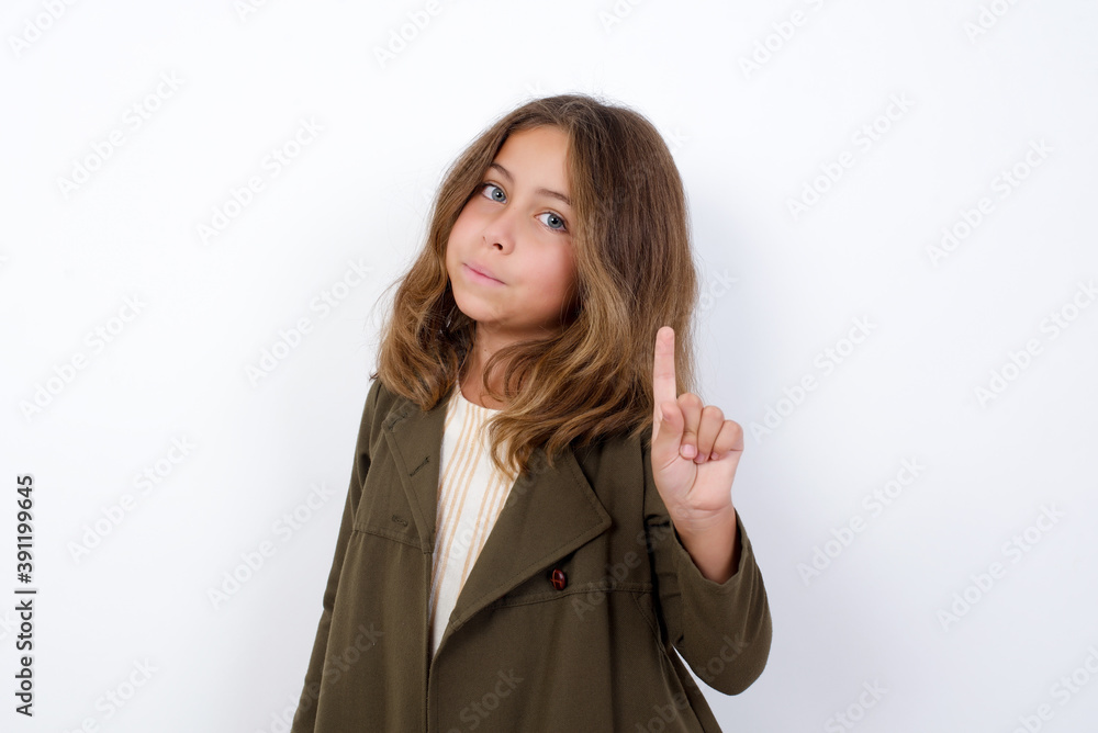 No sign gesture. Closeup portrait unhappy Beautiful little girl standing against white background, raising fore finger up saying no. Negative emotions facial expressions, feelings. No sign gesture. Closeup portrait unhappy Beautiful little girl standing against white background, raising fore finger up saying no. Negative emotions facial expressions, feelings.