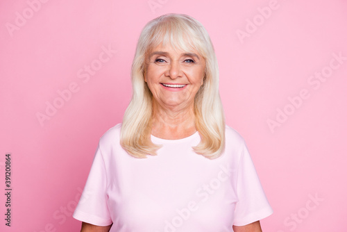 Photo portrait of cute granny with blonde hair smiling happily wearing white t-shirt isolated on pastel pink color background