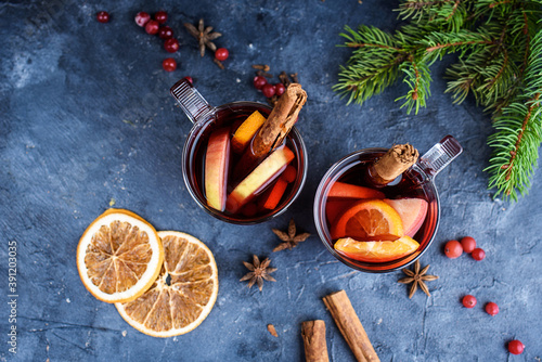 wo cups of christmas mulled wine or gluhwein with spices and orange slices on rustic table top view. Traditional drink on winter holiday