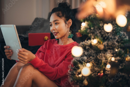 Woman making video call on social network and giving Christmas gift on Christmas day. Happy girl celebrating Christmas from social network.