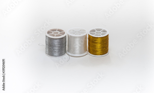 Three coils with white, gold and silver threads on a white background