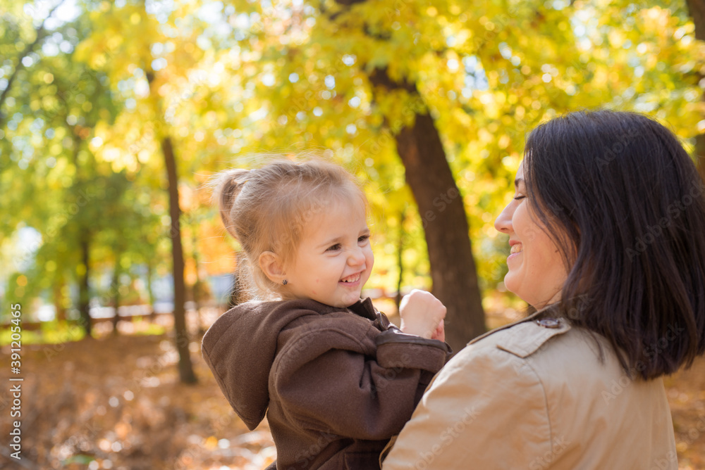 A young mother and little daughter are walking and laughing in the autumn park. Family. Autumn mood A young mother and little daughter are walking and laughing in the autumn park. Family. Autumn mood