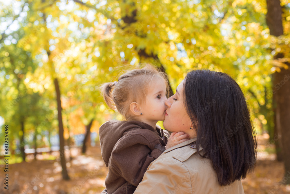 A young mother and little daughter are walking and laughing in the autumn park. Family. Autumn mood A young mother and little daughter are walking and laughing in the autumn park. Family. Autumn mood