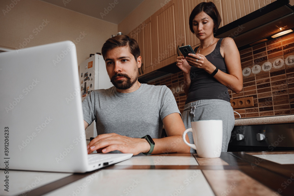 Couple at kitchen, reading news and using laptop. Couple at kitchen, reading news and using laptop.
