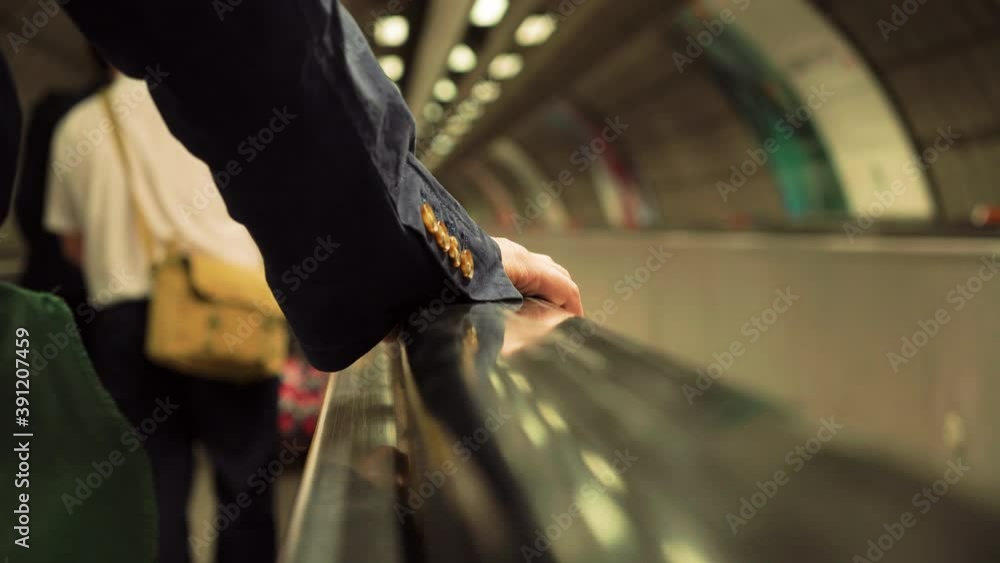 Traveling on a horizontal escalator on the London Underground, suit sleeve and hand visible of male rider. Traveling on a horizontal escalator on the London Underground, suit sleeve and hand visible of male rider.