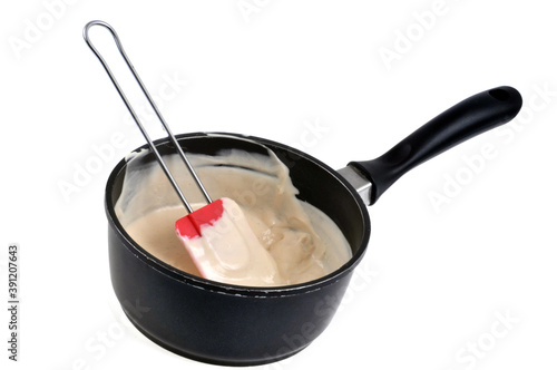 Casserole de sauce béchamel avec une spatule en gros plan sur fond blanc