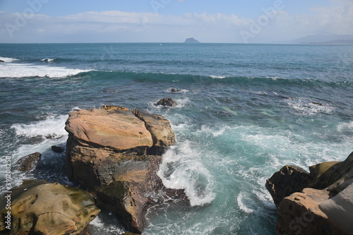 From Guihou Coast, you can see the beautiful Keelung Island bathed in blue sky and white clouds. The waves slapped against the rocky shore. photo