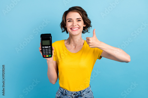 Photo of positive girl hold card reader raise thumb up wear yellow t-shirt isolated blue color background