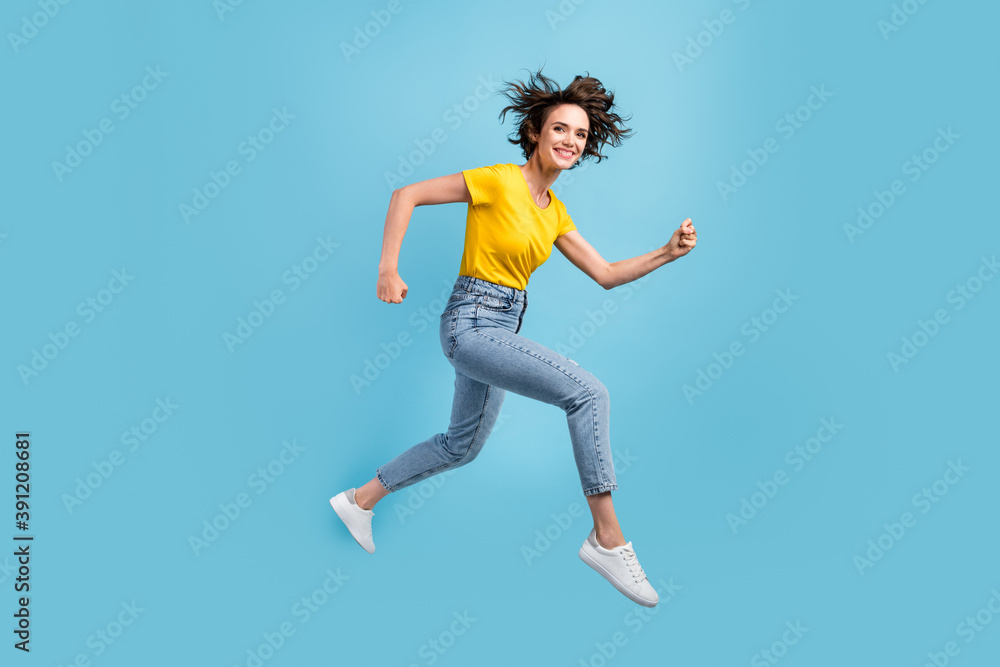 Full length profile photo of girl jump rush run fists wear yellow t-shirt denim jeans footwear isolated blue color background