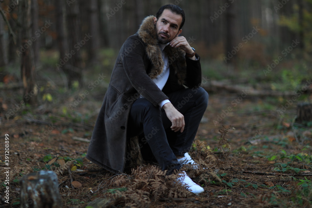 Fototapeta premium Przystojny mężczyzna w brązowym płaszczu z futerkiem. 