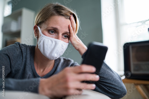 Stressed woman with smartphone indoors at home, mental health and coronavirus concept.