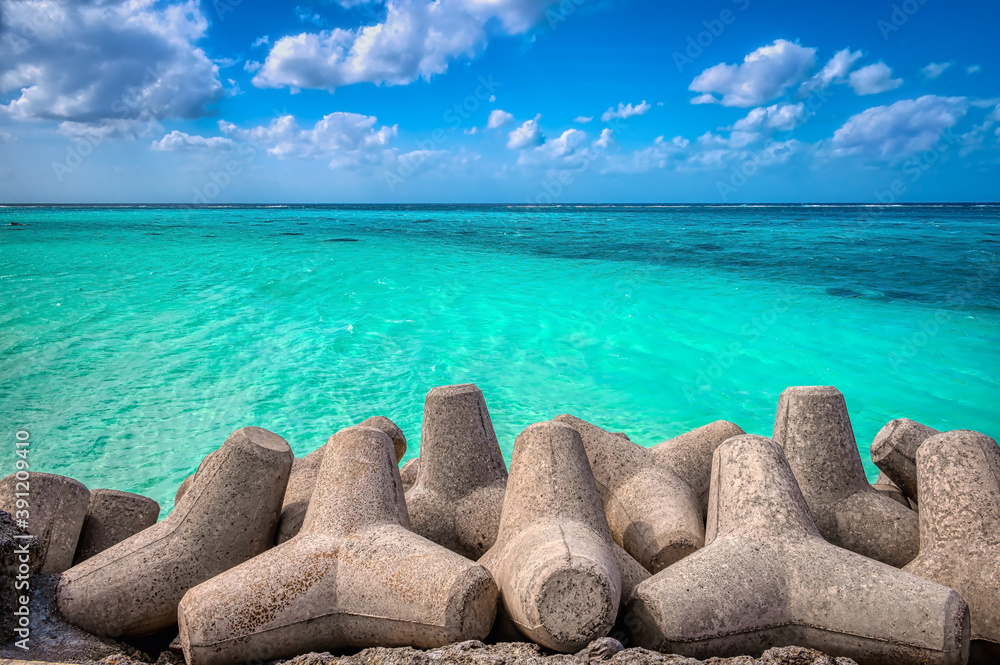 Fototapeta premium Sea wall defense concrete tetrapods contrast with the pristine waters and white sandy beaches of Shimojishima Island, Miyakojima, Okinawa, near the Shimojishima airport