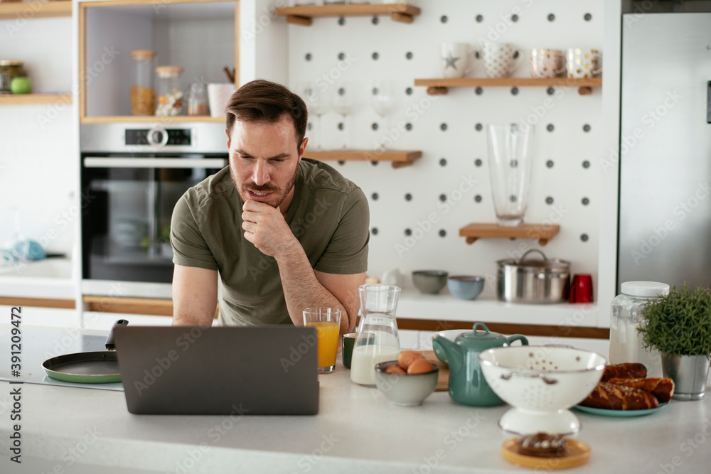 Young man eating breakfast and reading the news online. Handsome man enjoying at home. Young man eating breakfast and reading the news online. Handsome man enjoying at home.
