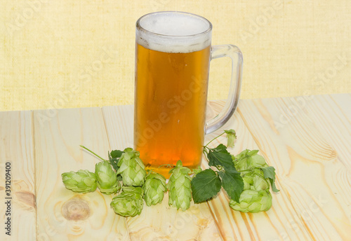 Glass mug of beer and hops cones on rustic table