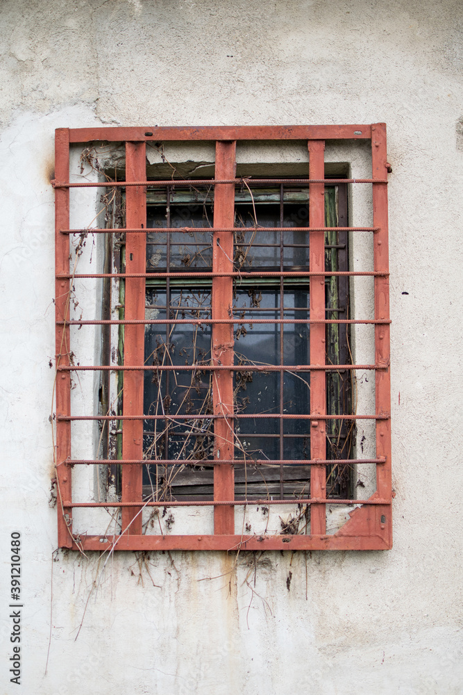 Obraz premium Grated window to an old abandoned warehouse. Rusty bars on the window