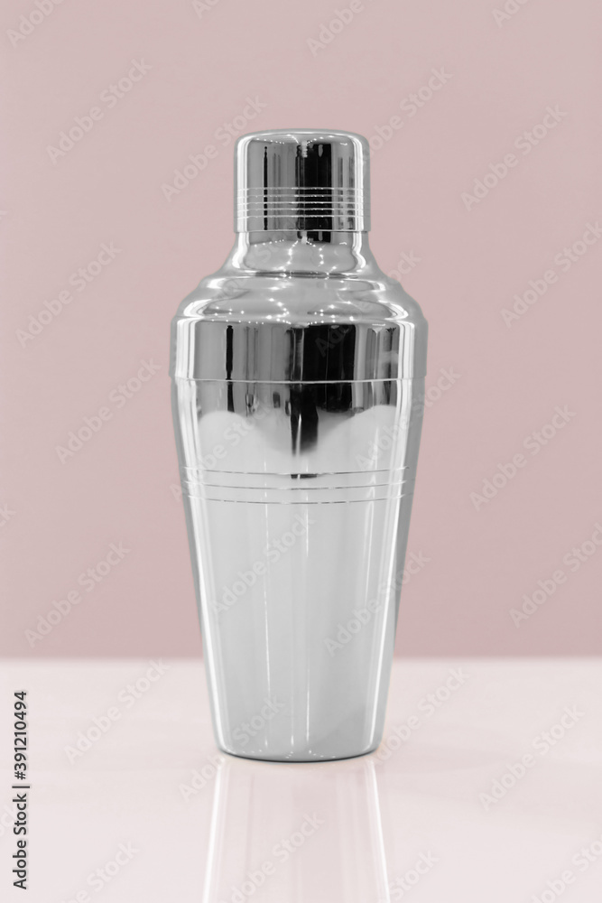 Shiny bar cocktail shaker golden and silver standing on a bar counter on a colourful background Shiny bar cocktail shaker golden and silver standing on a bar counter on a colourful background