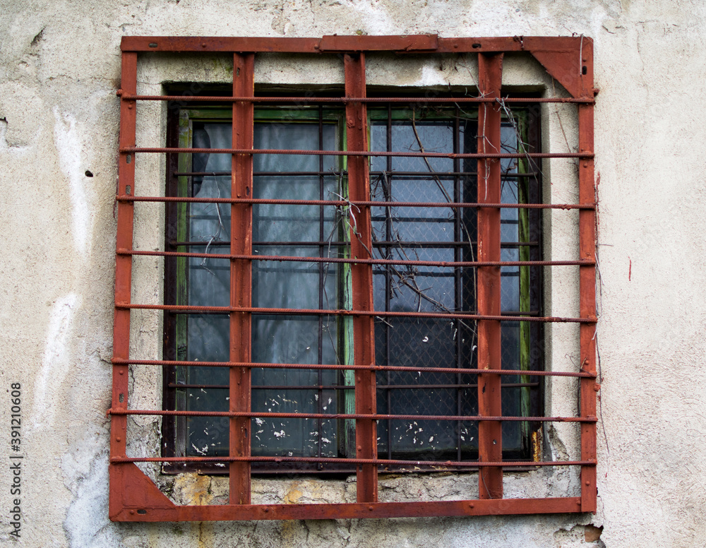 Grated window to an old abandoned warehouse. Rusty bars on the window