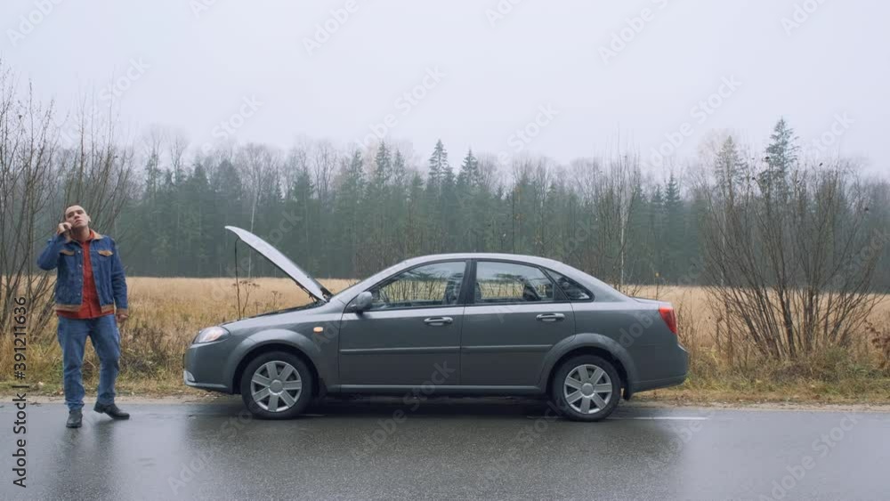 Young man on countryside road trying to get help with her broken down car and call evacuation Young man on countryside road trying to get help with her broken down car and call evacuation