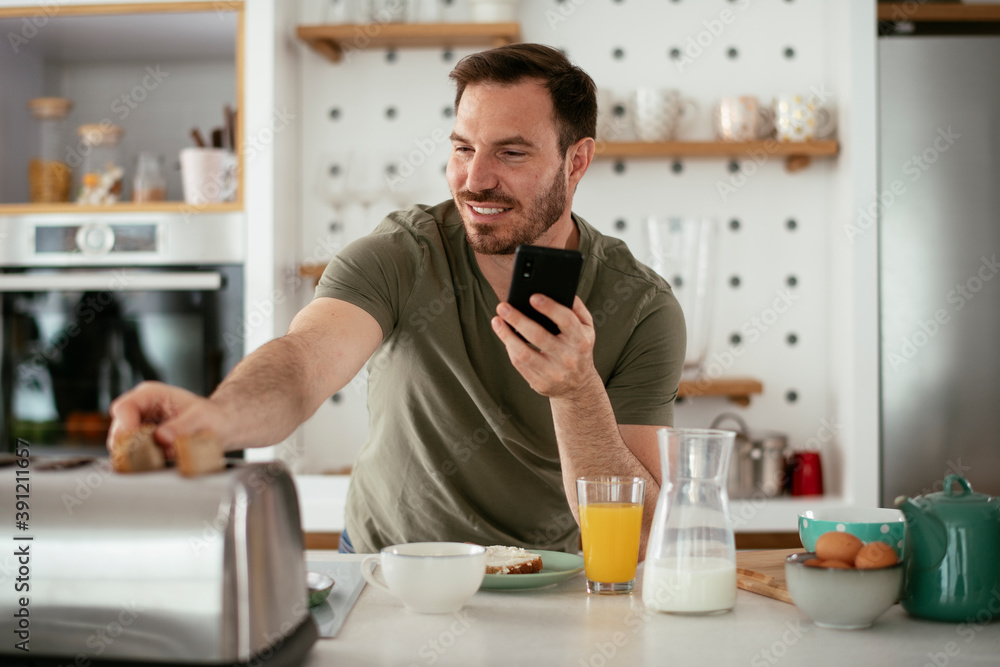 Young man eating breakfast and reading the news online. Handsome man enjoying at home. Young man eating breakfast and reading the news online. Handsome man enjoying at home.