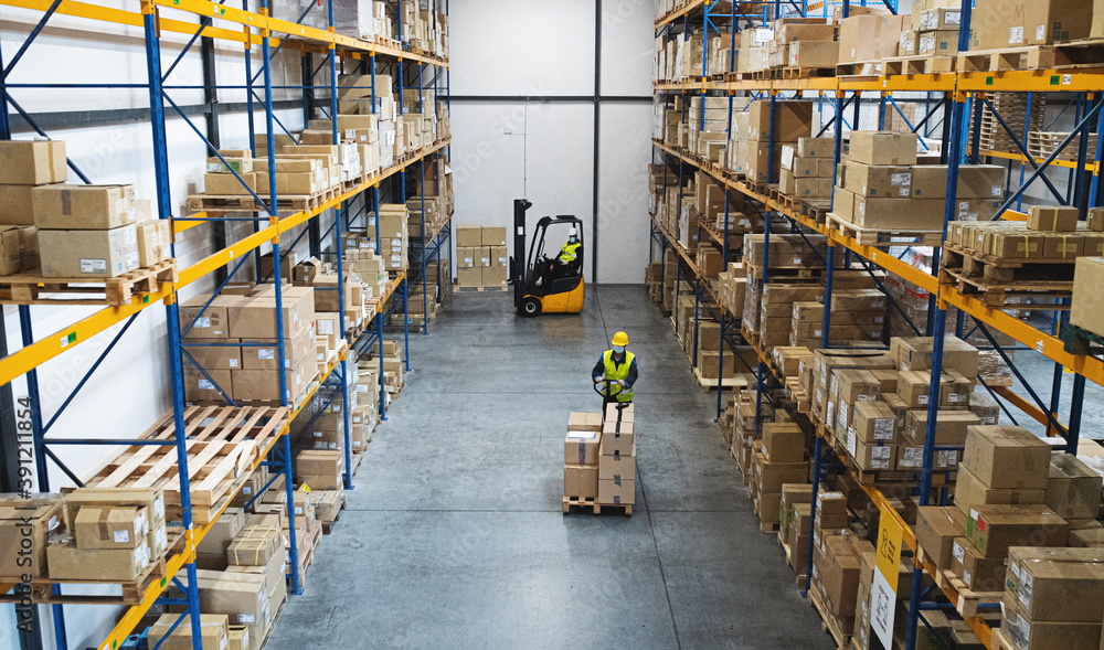 Men workers with forklift and pallet truck working indoors in warehouse, coronavirus concept. Men workers with forklift and pallet truck working indoors in warehouse, coronavirus concept.