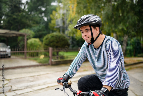 Fototapeta Naklejka Na Ścianę i Meble -  Portrait of down syndrome adult man with bicycle cycling outdoors on street.